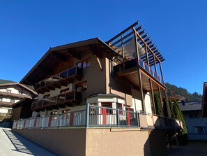 A multi-story building with balconies, a wooden facade, and a clear blue sky in the background. - Nice apartment with terrace in prime location (Viehhofen)