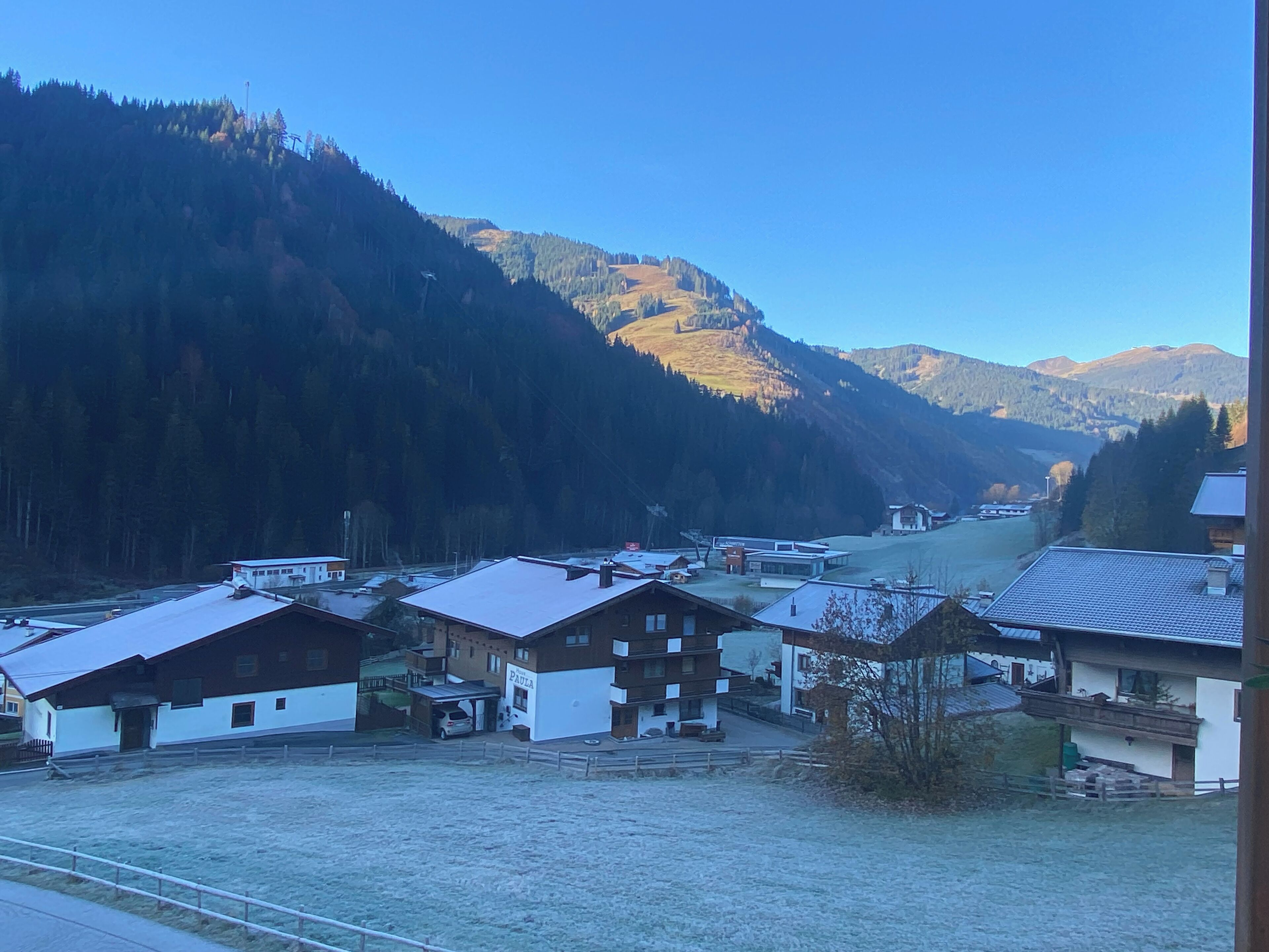 A rural village with traditional houses, a clear sky, and mountains in the background.