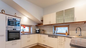 Una cocina moderna con armarios blancos, un horno Bosch, una cafetera y una ventana con vistas.
