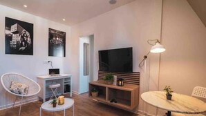 Un salon moderne doté d’un téléviseur à écran plat, de meubles blancs et d’œuvres d’art accrochées aux murs.