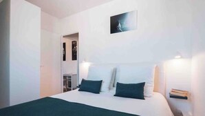 Une chambre à coucher comprenant un lit, deux tables de chevet, une petite table et une œuvre d’art accrochée au mur.