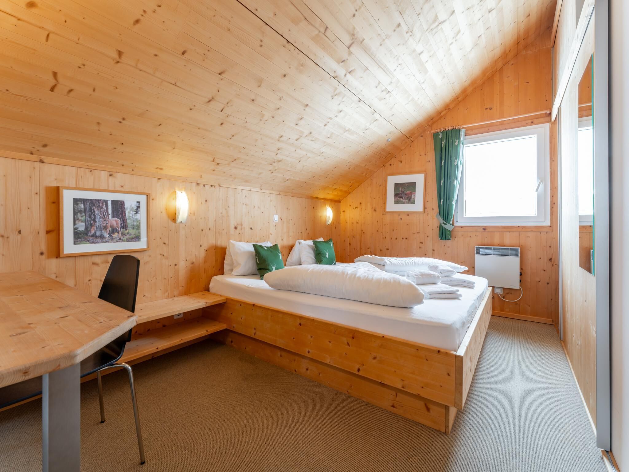 A wooden room with a bed, a desk, and a chair.