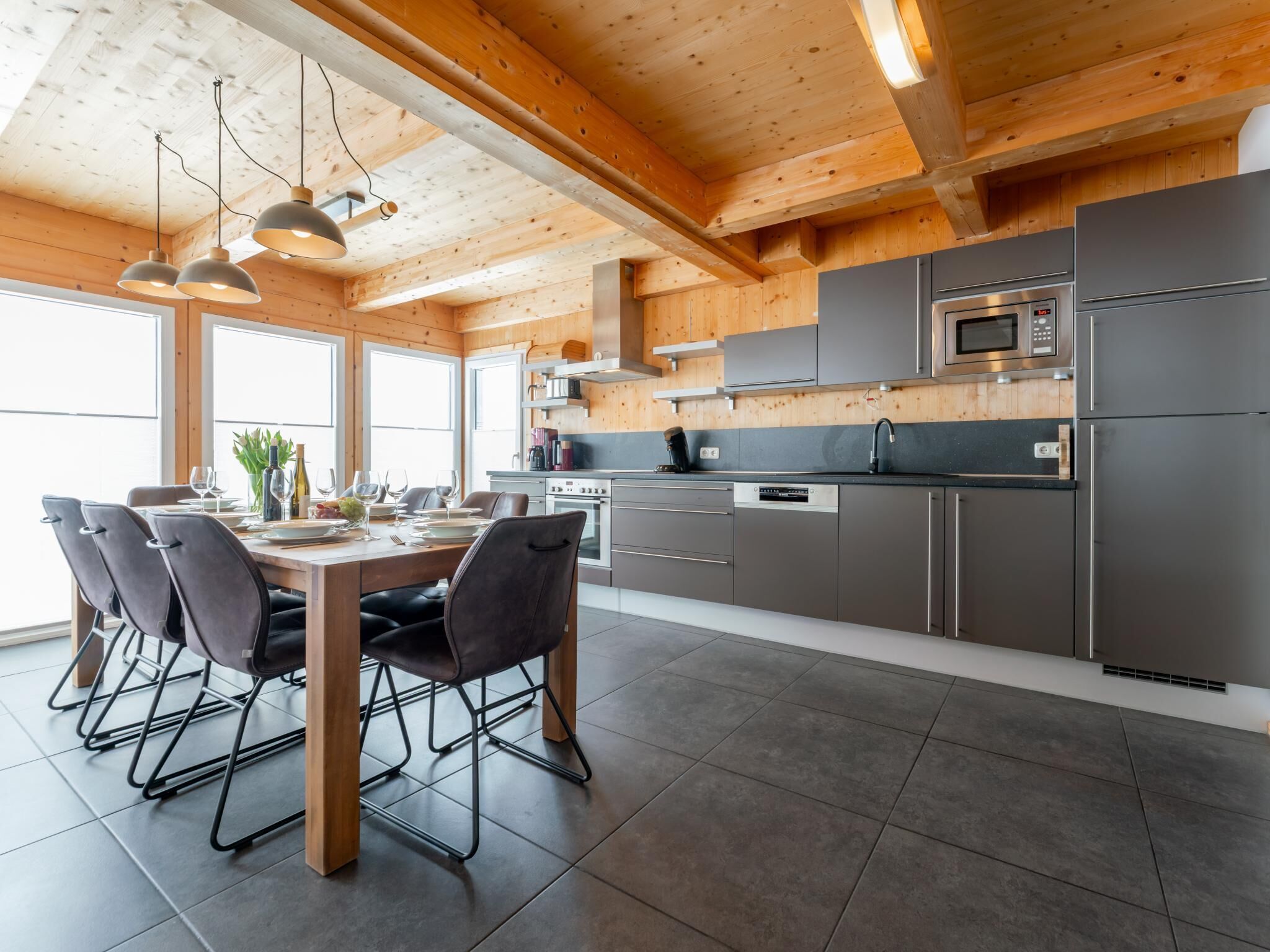 Una cocina moderna con vigas de madera, electrodomésticos de acero inoxidable y un comedor con mesa y sillas.