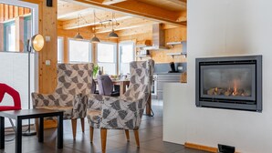 A modern interior with a fireplace, wooden ceiling beams, and patterned chairs.