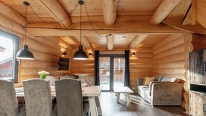 A log cabin interior with a dining area, sofa, and a television.
