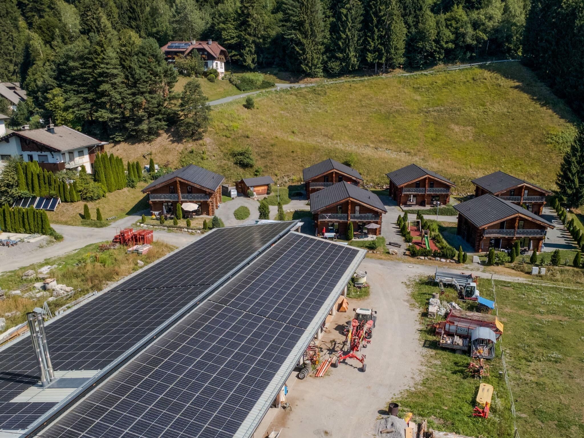 Eine große Solaranlage, Holzblockhäuser und eine hügelige Landschaft.