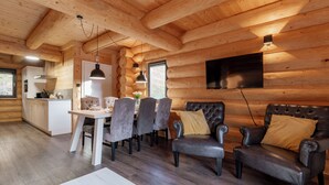 A log cabin interior with a dining area, kitchen, and seating area.