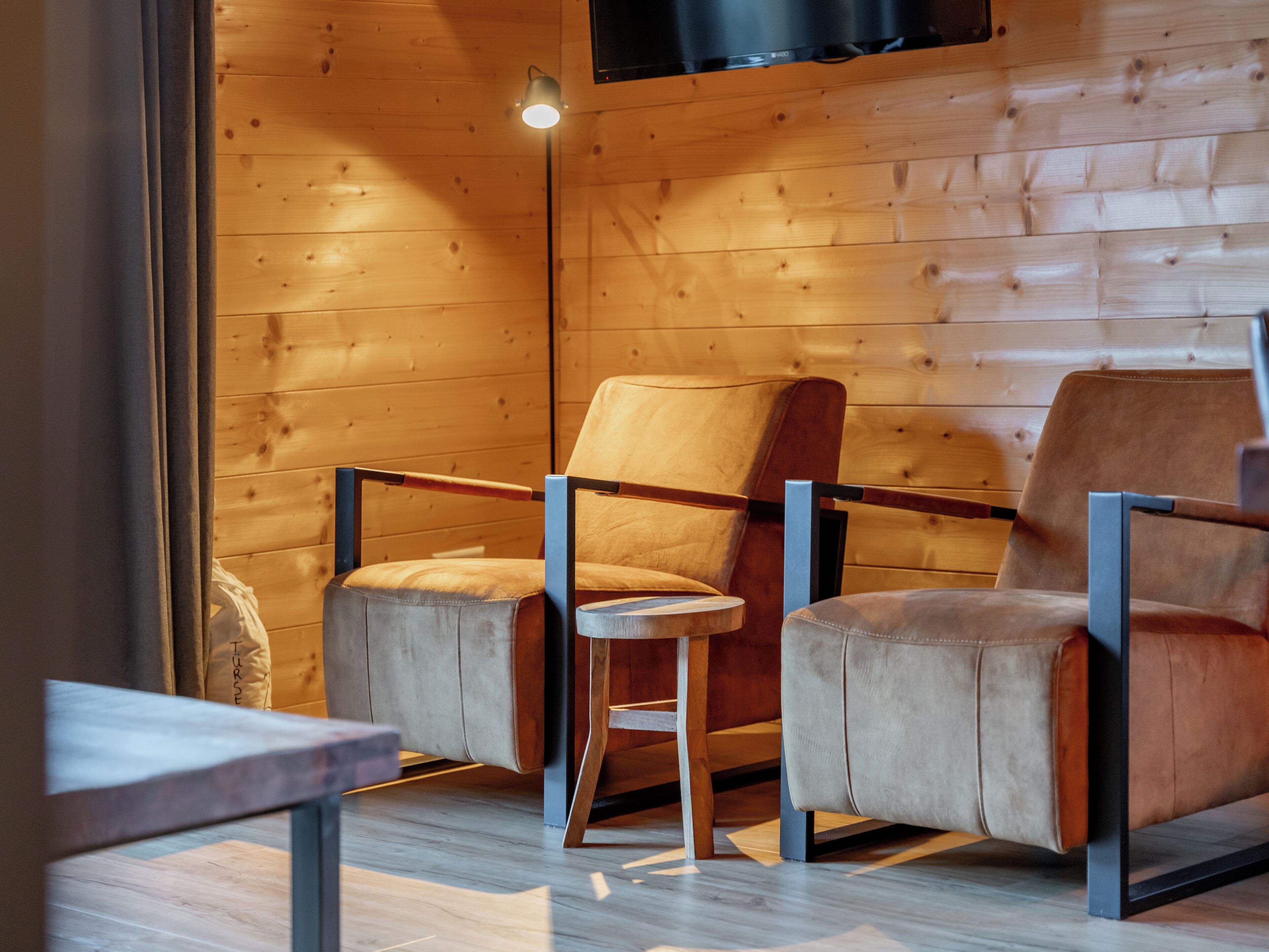 A modern interior with wooden walls and two leather chairs with metal frames.