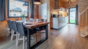 Une cabane en bois comprenant un coin repas, une cuisine et offrant une vue sur l’extérieur.
