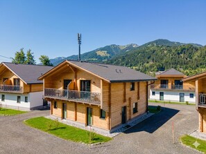 Eine Reihe von Holzhütten mit Balkonen vor einer Bergkulisse.