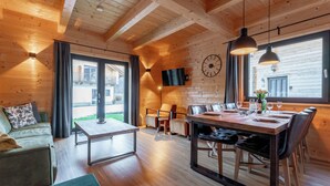 Un intérieur chaleureux, avec des murs en bois, un coin repas, un canapé et un téléviseur fixé au mur.
