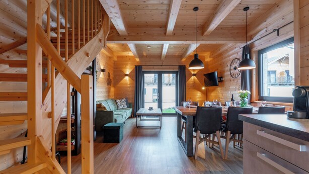 L’intérieur d’un chalet en bois chaleureux et accueillant, avec un escalier, un coin repas et un salon.