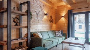 L’intérieur d’un chalet chaleureux, avec un canapé vert, des étagères en bois et une petite table.