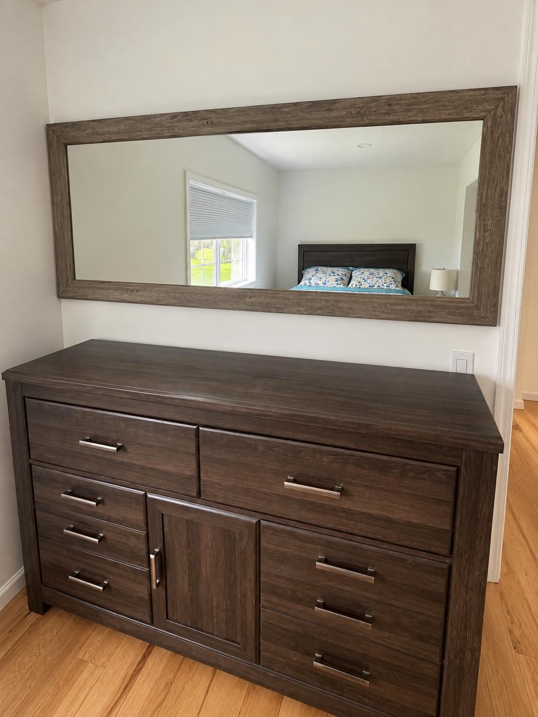 A dark wooden dresser with multiple drawers and a large mirror above it.