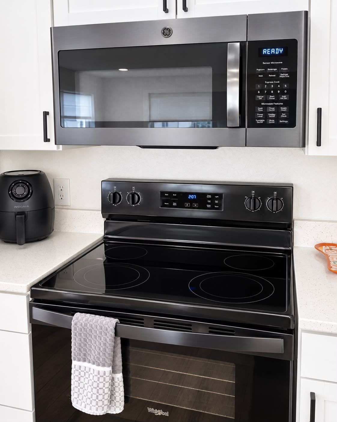 A kitchen with a GE microwave, a black stove, and an oven.