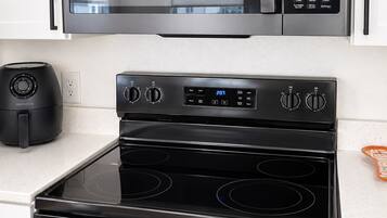 A kitchen with a GE microwave, a black stove, and an oven.