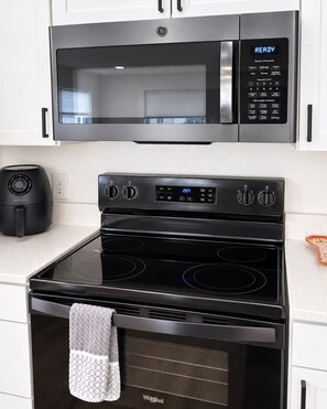 A kitchen with a GE microwave, a black stove, and an oven.