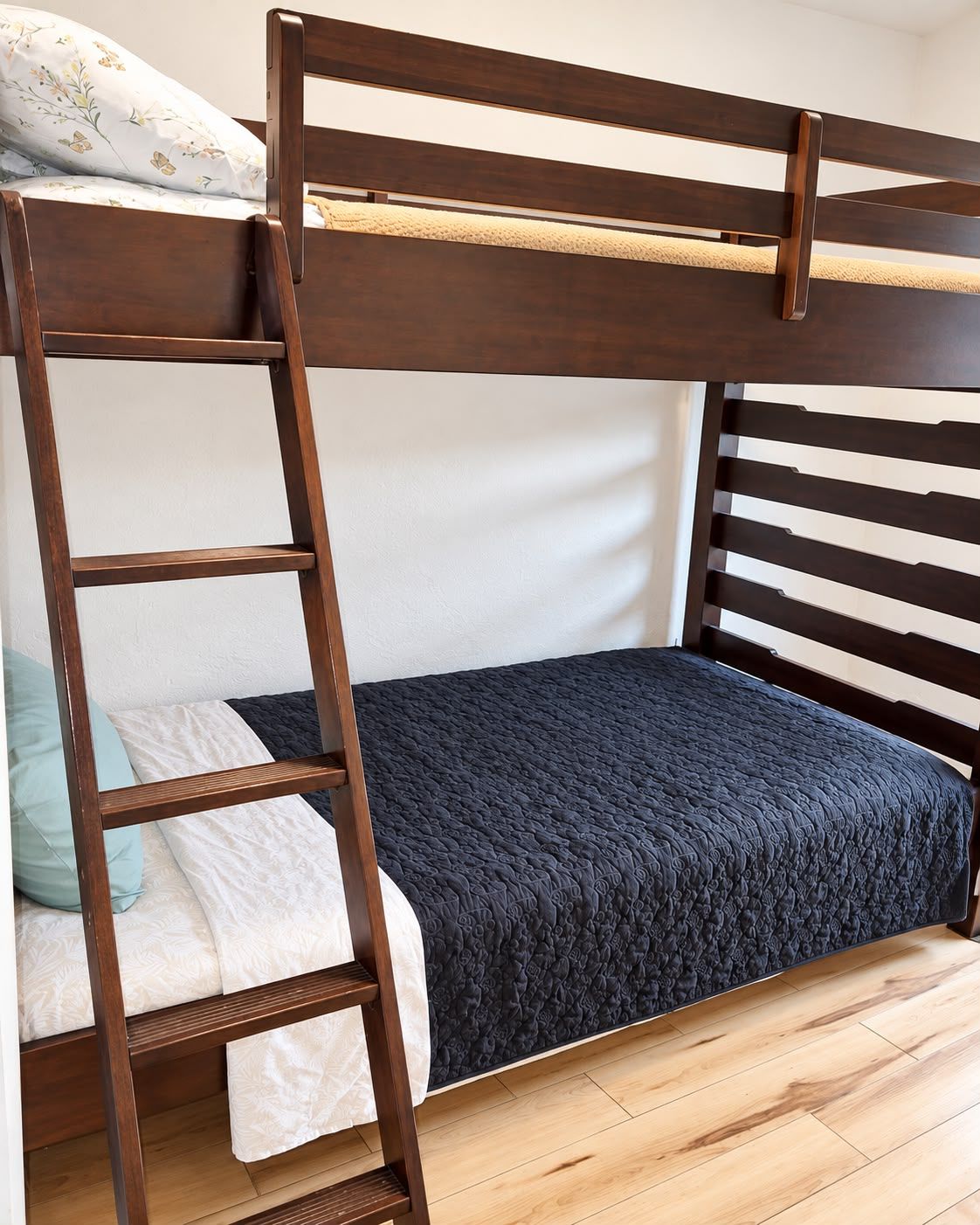 A bunk bed with a ladder, a dark mattress, and a white pillow.