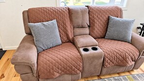 A brown sofa with a quilted pattern and two circular cutouts on the armrest. - Modern 2 Bedroom house in ANC (Anchorage)