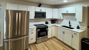 Une cuisine moderne avec des armoires blanches, des appareils en acier inoxydable et un plancher en bois.