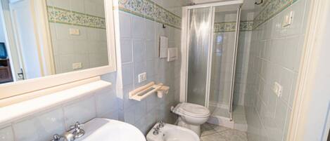 A bathroom with a bathtub, a toilet, and a shower area.