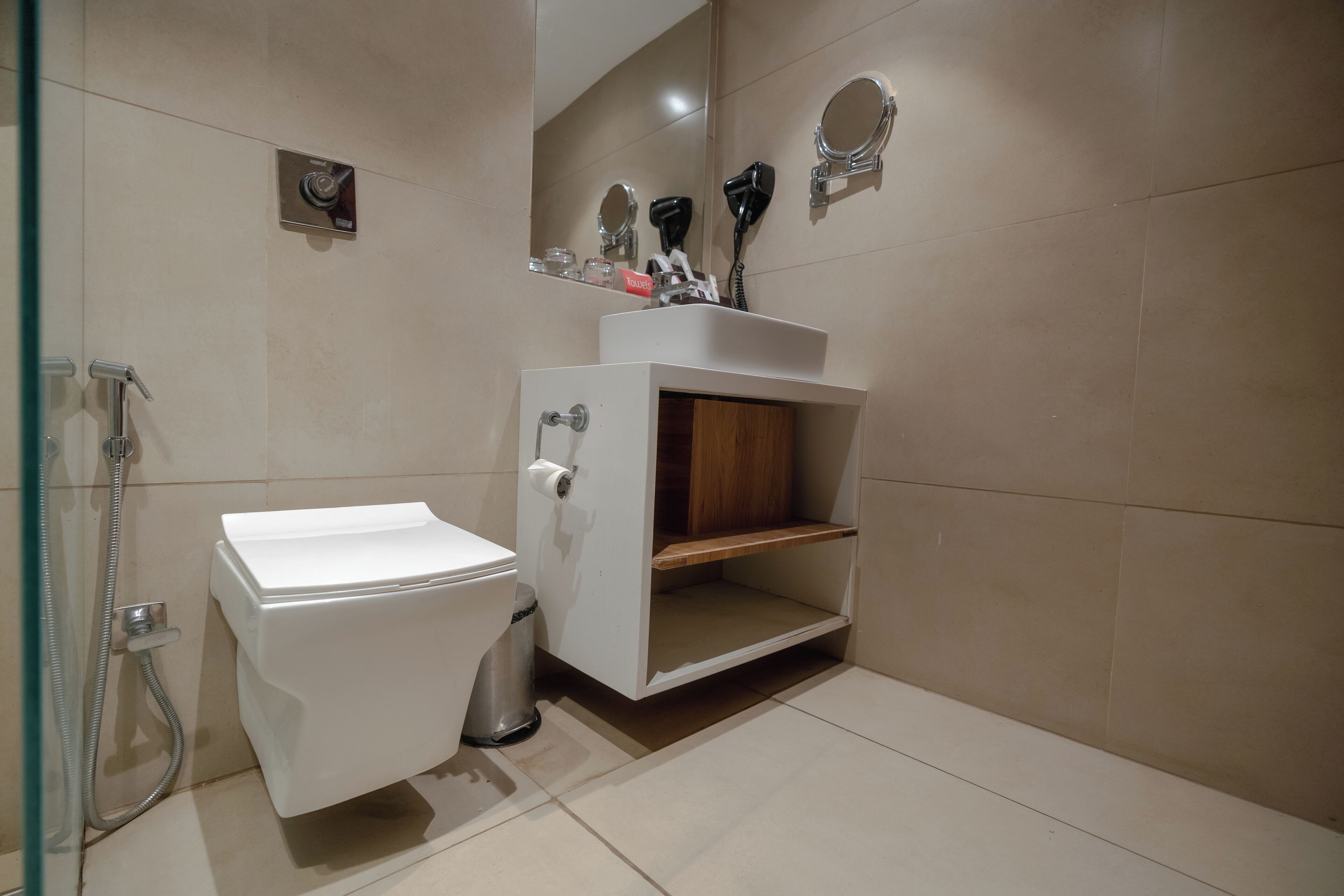 A modern bathroom with a toilet, bidet, and a vanity with a mirror and hairdryer.