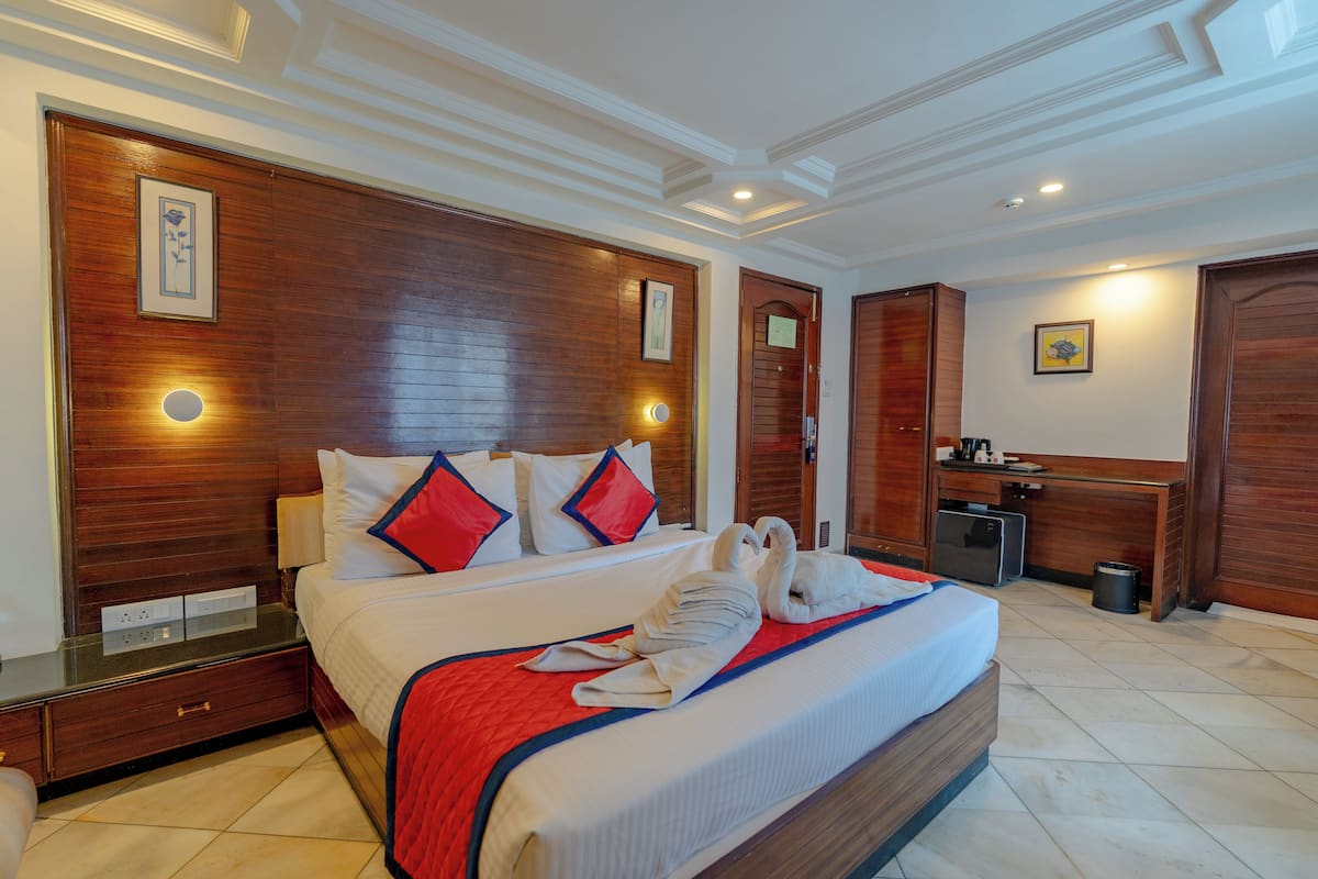 A hotel room with a large bed, wooden headboard, and a desk with a chair.