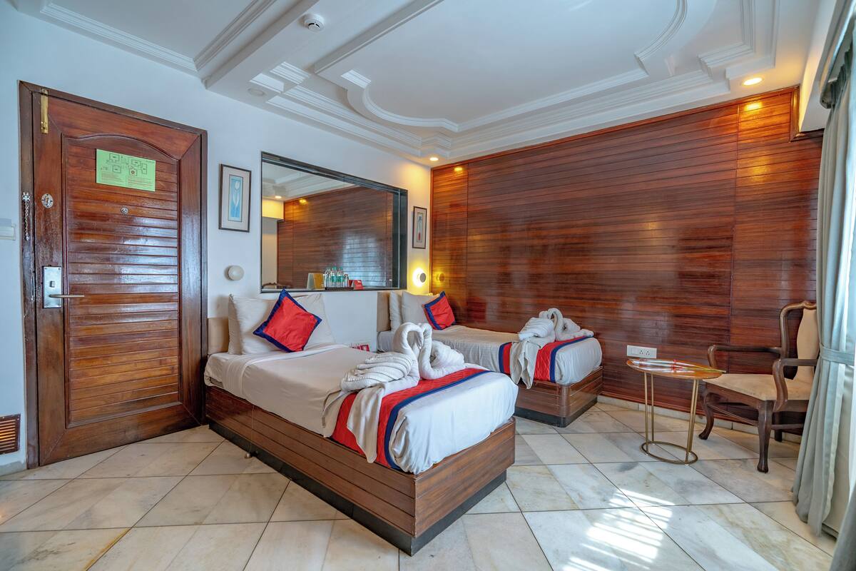 A hotel room with two beds, a wooden panel wall, a small table, and a chair.