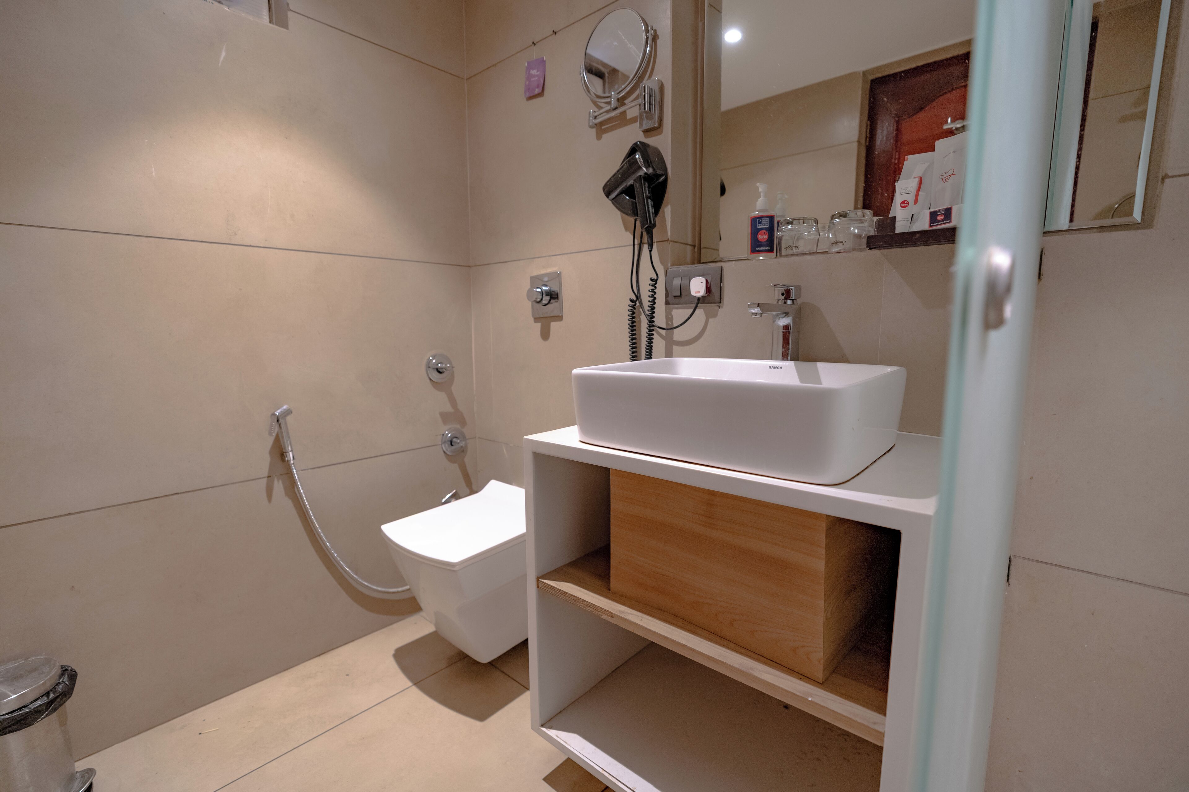 A modern bathroom with a white sink, a handheld showerhead, and a toilet.
