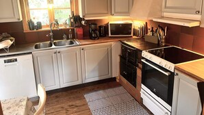 A compact kitchen with white cabinets, a microwave, a stove, and a sink. - 8 Person Holiday Home in Salen (Salen)