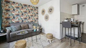 A modern living room with a grey sofa, a round coffee table, and a dining area with a bar stool. - TheBlueStay 144 - Cosy cocoon in Asnières (Paris)