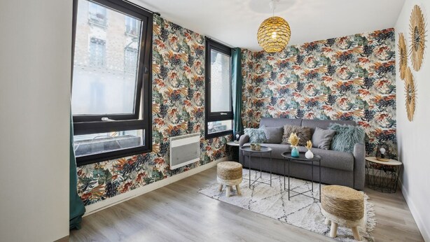 A modern living room with large windows, a grey sofa, a round coffee table, and a tropical wallpaper design. - TheBlueStay 144 - Cosy cocoon in Asnières (Paris)