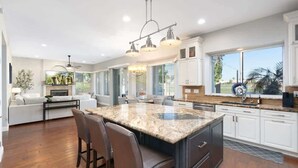 A spacious kitchen with a large island, white cabinetry, and a view of the outdoors. - Golf Course Oasis | Pool, Spa, EV & Family Fun (Goodyear)
