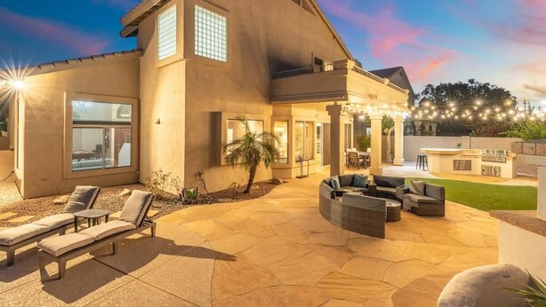 A modern house with a patio area featuring outdoor furniture and a barbecue. - Golf Course Oasis | Pool, Spa, EV & Family Fun (Goodyear)