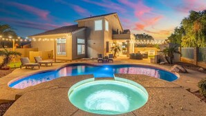 A modern house with a swimming pool, outdoor seating, and string lights. - Golf Course Oasis | Pool, Spa, EV & Family Fun (Goodyear)