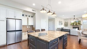 A spacious kitchen with a large island, stainless steel appliances, and a modern chandelier. - Golf Course Oasis | Pool, Spa, EV & Family Fun (Goodyear)