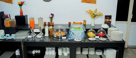 A buffet setup with various food items, utensils, and containers.