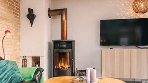 Un salon chaleureux avec un poêle à bois, un téléviseur à écran plat et un coin salon confortable.
