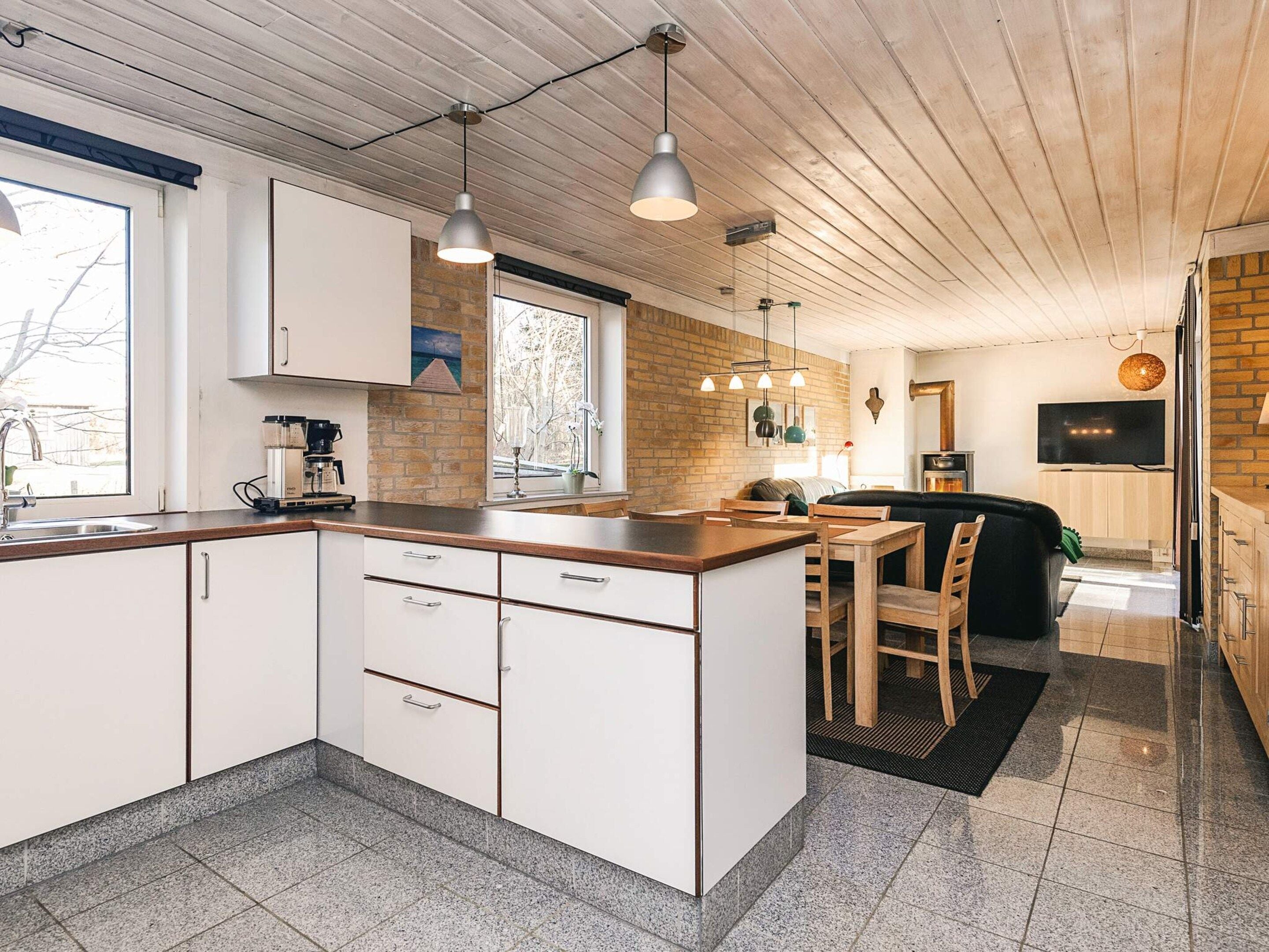 A modern kitchen with white cabinets, a granite countertop, and pendant lighting.