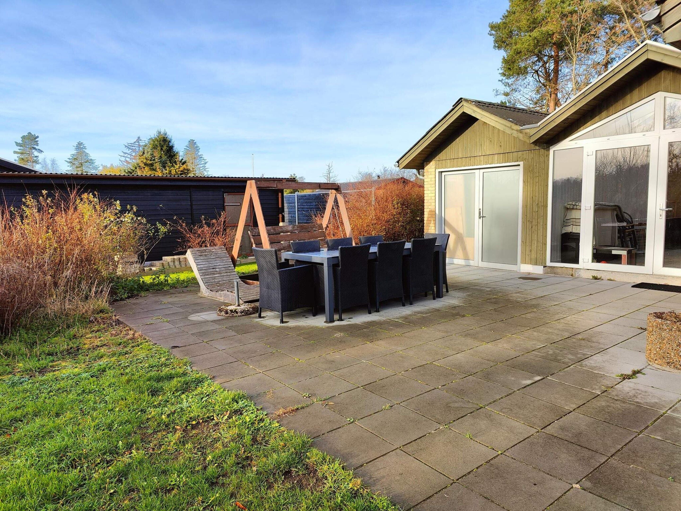 A patio area with a table and chairs, a wooden swing set, and a garage door.