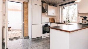 Une cuisine moderne avec des meubles blancs, un four encastré et un grand îlot central.