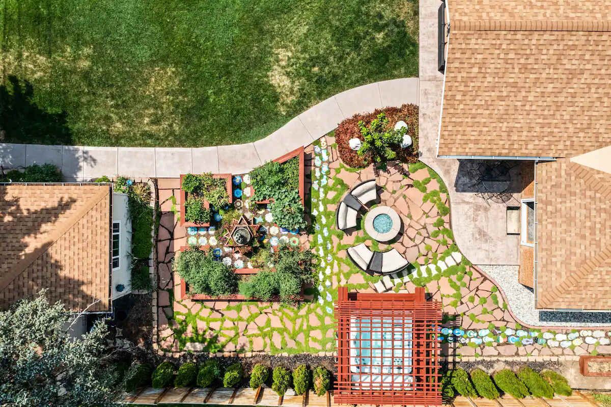 An aerial view of a landscaped outdoor area with a pool, seating, and a red gate.