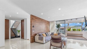 Una sala de estar moderna con un muro de acento de madera, un ventanal que da a un balcón y una escalera.