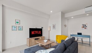 A modern living room with a flat-screen TV, a sofa, a coffee table, and a desk with a laptop. - Maralma 903: Panoramic Views and Rooftop Pool (Bucerías)