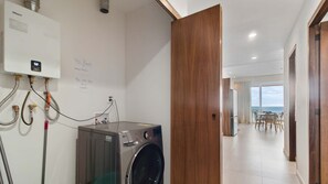A laundry area with an LG washing machine, a water heater, and handwritten notes on the wall. - Maralma 903: Panoramic Views and Rooftop Pool (Bucerías)