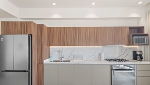 A modern kitchen with a built-in refrigerator, a microwave, and a gas stove. - Maralma 903: Panoramic Views and Rooftop Pool (Bucerías)