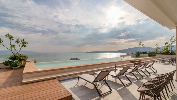 A rooftop pool area with lounge chairs and potted plants, overlooking a beach and ocean. - Maralma 903: Panoramic Views and Rooftop Pool (Bucerías)