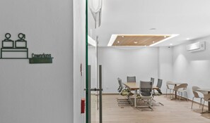 A modern conference room with a glass partition, a whiteboard, and a sign indicating a coworking space. - Maralma 903: Panoramic Views and Rooftop Pool (Bucerías)
