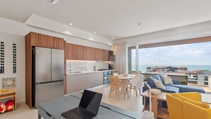 A modern apartment with a kitchen, dining area, and living room. It features a large window with a view of the sea. - Maralma 903: Panoramic Views and Rooftop Pool (Bucerías)