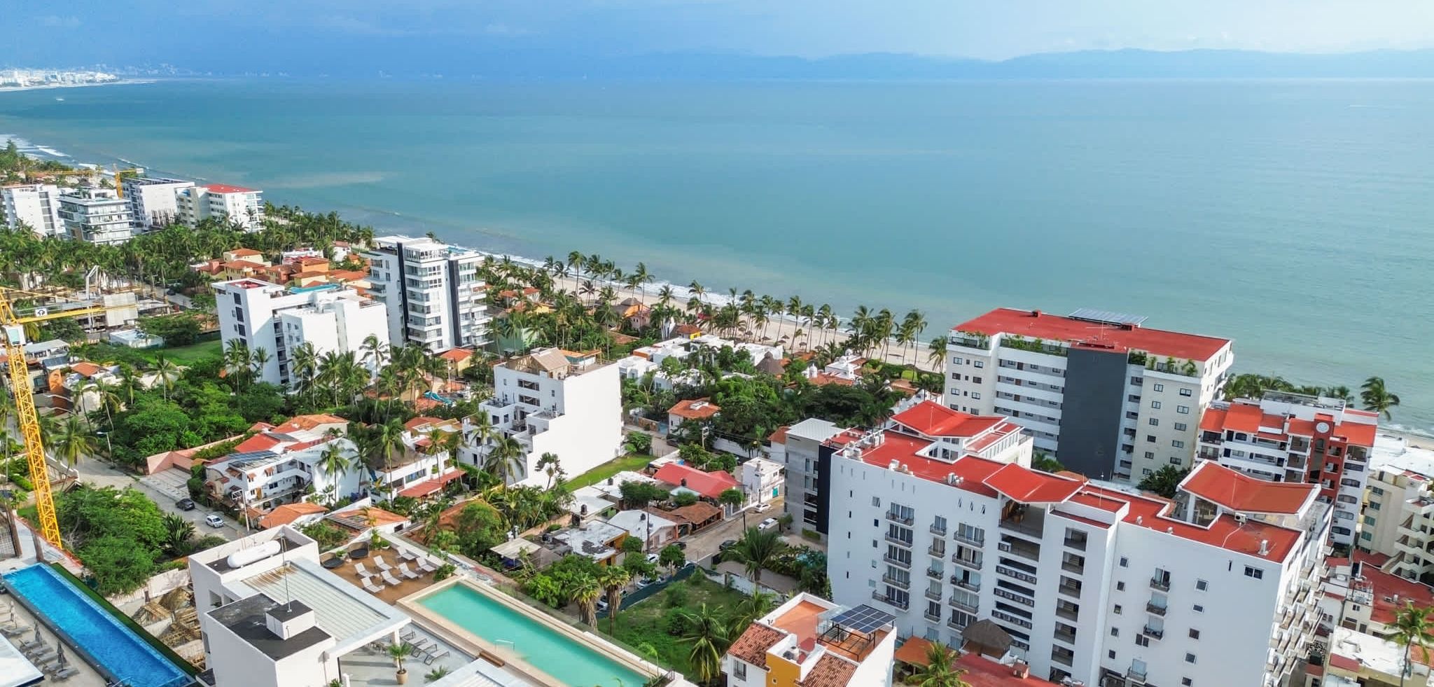 Un área residencial costera con varios edificios, una piscina y vista al mar.